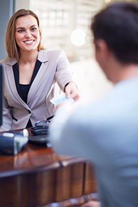 Branch employee smiling while assisting customer - NCR ITM service supports the entire branch